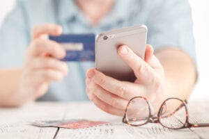 Close up male hands holding credit card and using mobile smart phone