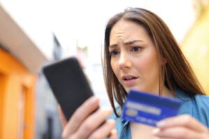 Worried woman pays online with credit card and smart phone